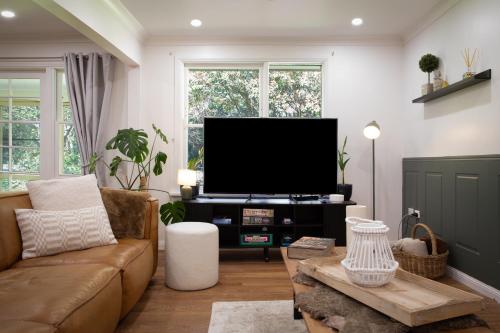 a living room with a couch and a flat screen tv at Highlands Heart Cottage in Bowral