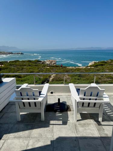 a man laying on a patio with two chairs and the ocean at 11 WESTCLIFF RENTALS in Hermanus