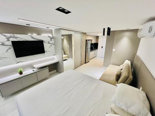 a bedroom with a white bed and a television at Unity - Flat Premium à Beira-Mar em Cabo Branco in João Pessoa