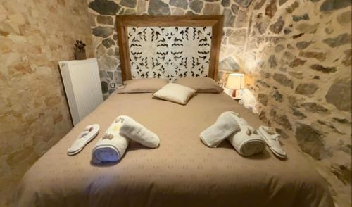 a bed with towels and slippers on it at STONE of KAMARIZA in Áyios Konstandínos