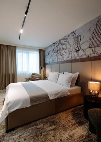 ein Schlafzimmer mit einem großen Bett und einem Gemälde an der Wand in der Unterkunft Hotel Savior in Vaslui