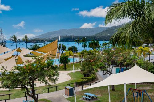 a park with white umbrellas and a playground at Bella Isola in Airlie Beach