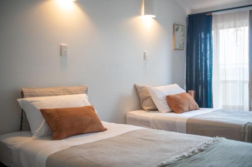 two beds in a room with a window at Bella Isola in Airlie Beach