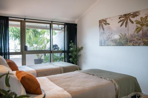 a room with two beds and a large window at Bella Isola in Airlie Beach