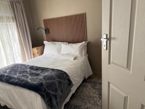 a bedroom with a bed with white pillows and a window at Bee Boutique Lodge in Nelspruit