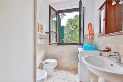 Un baño con lavabo, inodoro y ventana. en Cotoncello in una posizione panoramica - Goelba, en Marciana