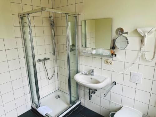 a bathroom with a glass shower and a sink at Hotel an der Rennbahn in Dresden