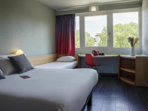 a hotel room with two beds and a window at Ibis Alès Centre Ville in Alès