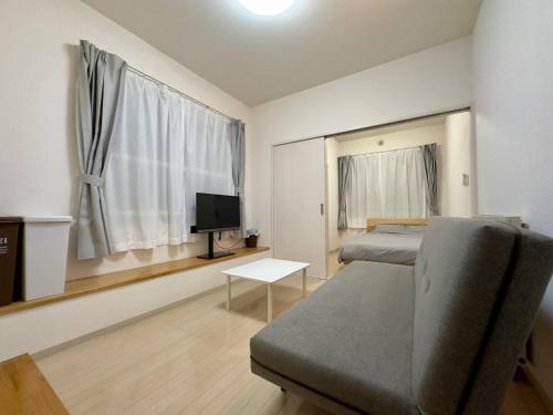 a bedroom with two beds and a tv and a couch at 401好立地札幌駅徒歩7分と大通駅徒歩6分で都心を満喫で綺麗な部屋で快適が生活が実現 in Sapporo