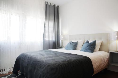 a bedroom with a large bed with blue pillows at Parque das Nações - Fil New Apartment in Lisbon