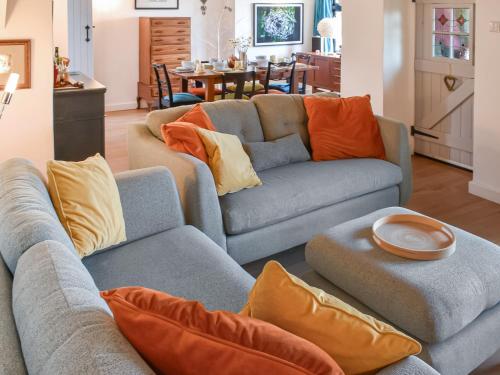 a living room with two couches and orange pillows at Rivendell Cottage in Liskeard