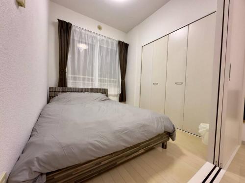a small bedroom with a bed and a window at 410札幌駅徒歩7分と大通駅徒歩6分で好立地な都心を満喫でき綺麗な部屋で快適が生活が実現 in Sapporo