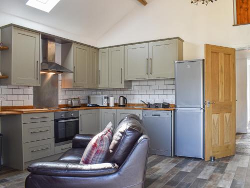 a kitchen with a leather couch and a refrigerator at The Dairy At Brook House Farm-Uk40631 in Church Minshull