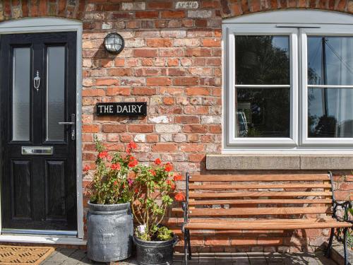 a brick building with a wooden bench next to a door at The Dairy At Brook House Farm-Uk40631 in Church Minshull
