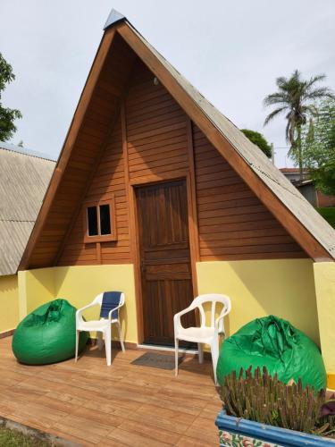 una casa con 2 sillas y un porche en Chalés Magia das Águas, en Águas de Lindóia