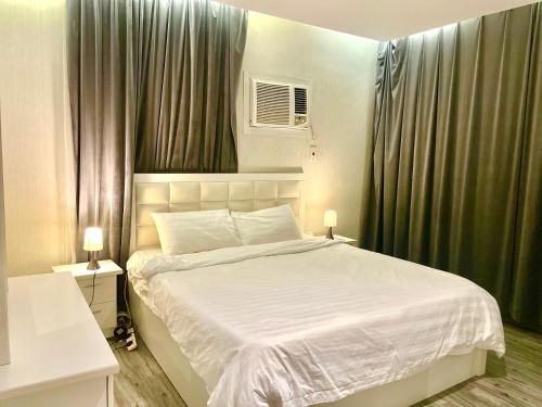a bedroom with a large white bed with green curtains at شقة 9 in Al-Safa
