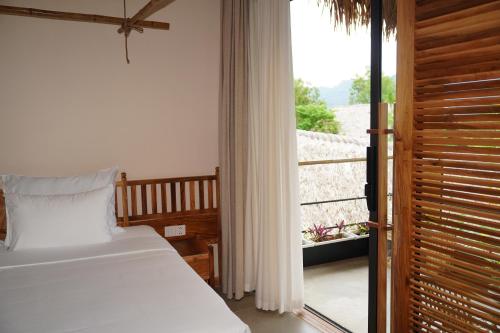 a bedroom with a bed and a view of a balcony at Vanlong garden in Kon Rung (1)