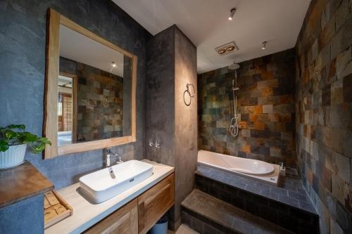 a bathroom with a sink and a tub and a mirror at Vanlong garden in Kon Rung (1)