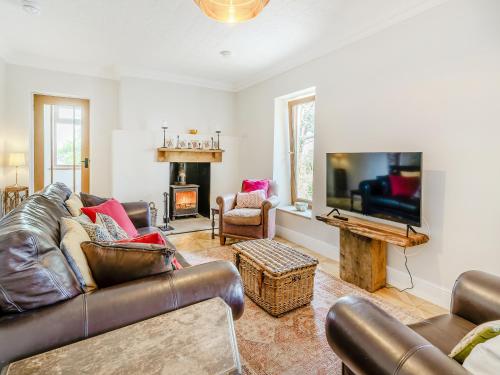 a living room with leather furniture and a flat screen tv at Halfstone House in Llanelli