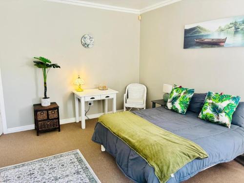 a bedroom with a bed and a table with a chair at Little Oasis - Palm Room in Port Elizabeth