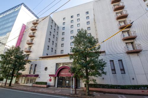 um grande edifício branco em uma rua da cidade em Nest Hotel Kumamoto em Kumamoto