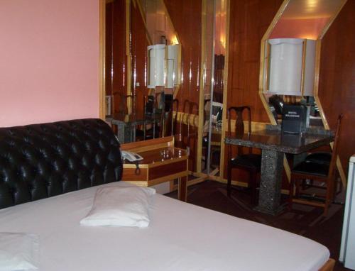 a bedroom with a bed and a desk and a mirror at motel millenium in Betim