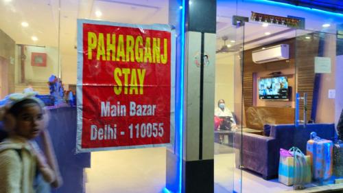 新德里Paharganj Stay - Main Bazar的商店玻璃门上的标志