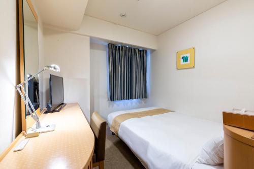 a hotel room with a bed and a television at Nest Hotel Kumamoto in Kumamoto