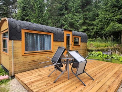 ein winziges Haus mit zwei Stühlen und einem Tisch auf einer Terrasse in der Unterkunft Brīvdienu namiņi Kalnozoli in Indrāni