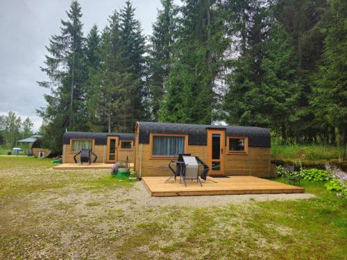 ein winziges Haus in einem Hof mit einer Holzterrasse in der Unterkunft Brīvdienu namiņi Kalnozoli in Indrāni