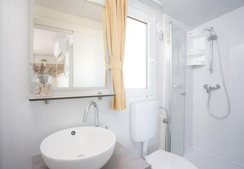 a white bathroom with a toilet and a sink at Valamar Camping Lanterna - Adriacamps in Poreč