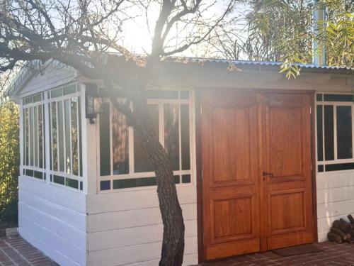 a small house with a wooden door next to a tree at YogaLife in Mercedes