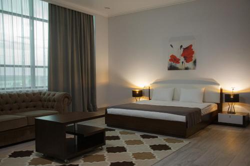 a hotel room with a bed and a couch at Baitau Hotel Aktobe in Aktobe