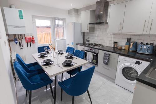 a kitchen with a dining table and blue chairs at Spacious 4 Bed House in Birmingham City Centre, Ideal for long term with Free Parking in Birmingham