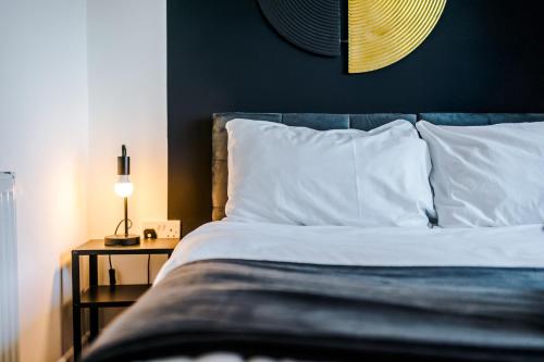 a bed with white pillows and a night stand with a lamp at Spacious 4 Bed House in Birmingham City Centre, Ideal for long term with Free Parking in Birmingham