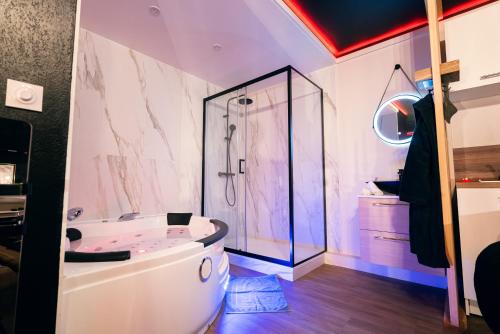 une salle de bain avec baignoire et douche en verre dans l'établissement Love room - Le secret du marquis, à Provins