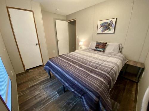 ein kleines Schlafzimmer mit einem Bett mit gestreifter Decke in der Unterkunft Off-Grid Cottage with Nice Sights in Dunnellon, Florida in Dunnellon