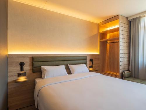 a bedroom with a large white bed with two pillows at Campanile Hotel & Restaurant Breda in Breda