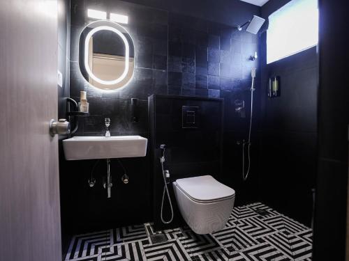 a bathroom with a toilet and a sink and a mirror at K Hotels by SYN in Bangalore