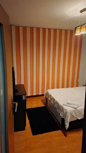 a bedroom with a bed and a striped wall at CasaLuxi in Alexandria