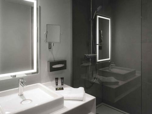 a bathroom with a sink and a shower and a mirror at Novotel Caen Côte de Nacre in Caen