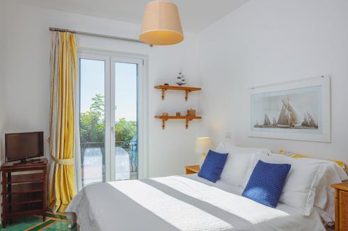 a bedroom with a bed with blue pillows and a window at POSEA Collection - Villa La Nice in Positano