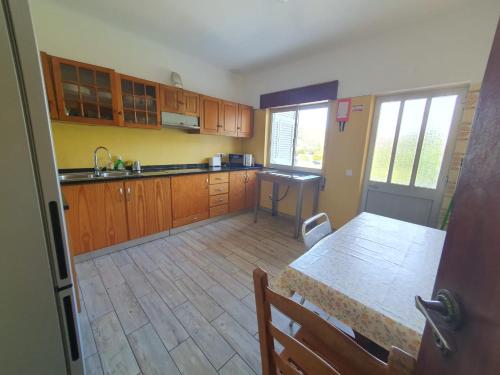 una cocina con armarios de madera y una mesa en una habitación en Surf Seixe Guest House, en Odeceixe