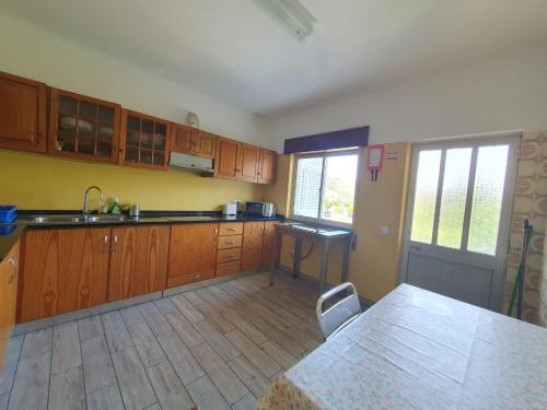 Una cocina con gabinetes de madera y una mesa en ella. en Surf Seixe Guest House, en Odeceixe