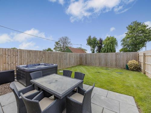 einen Hinterhof mit einem Tisch, Stühlen und einem Zaun in der Unterkunft The Stone Barn 