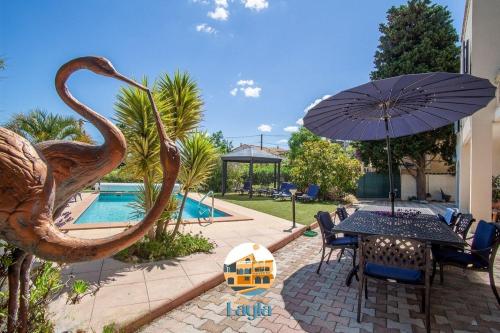 a statue of a bird sitting on a table with an umbrella at Villa Layla - 5 étoiles - 10 personnes - Vue mer in Sète