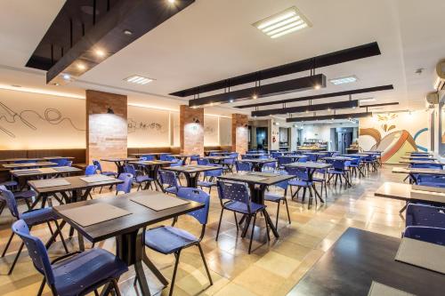 a dining room with tables and blue chairs at Hotel Dom Rafael Business in Santa Maria