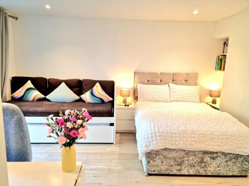a bedroom with a bed and a couch and a vase of flowers at Morden Place, Free Parking & Private Entrance in Bournemouth