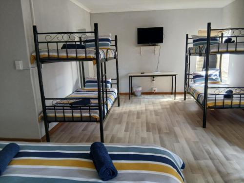 a room with three bunk beds and a flat screen tv at Bedrock inn in Harrismith