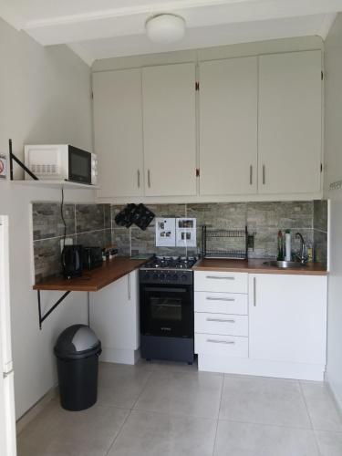 a kitchen with white cabinets and a stove top oven at Bedrock inn in Harrismith